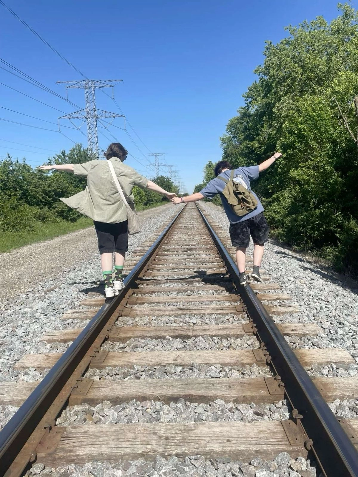 A couple of people that are standing on a train track.