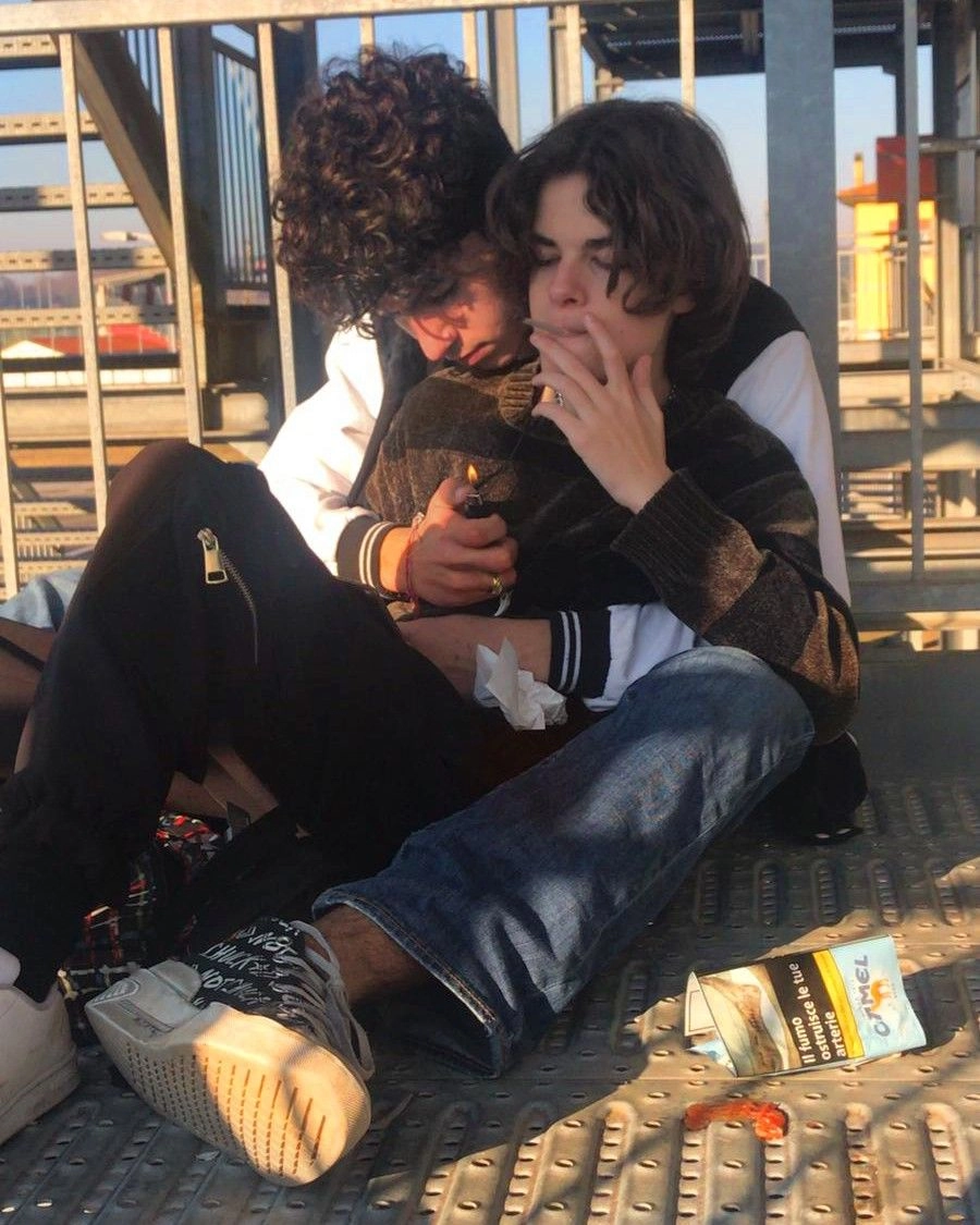 A couple of people sitting on top of a metal fence.