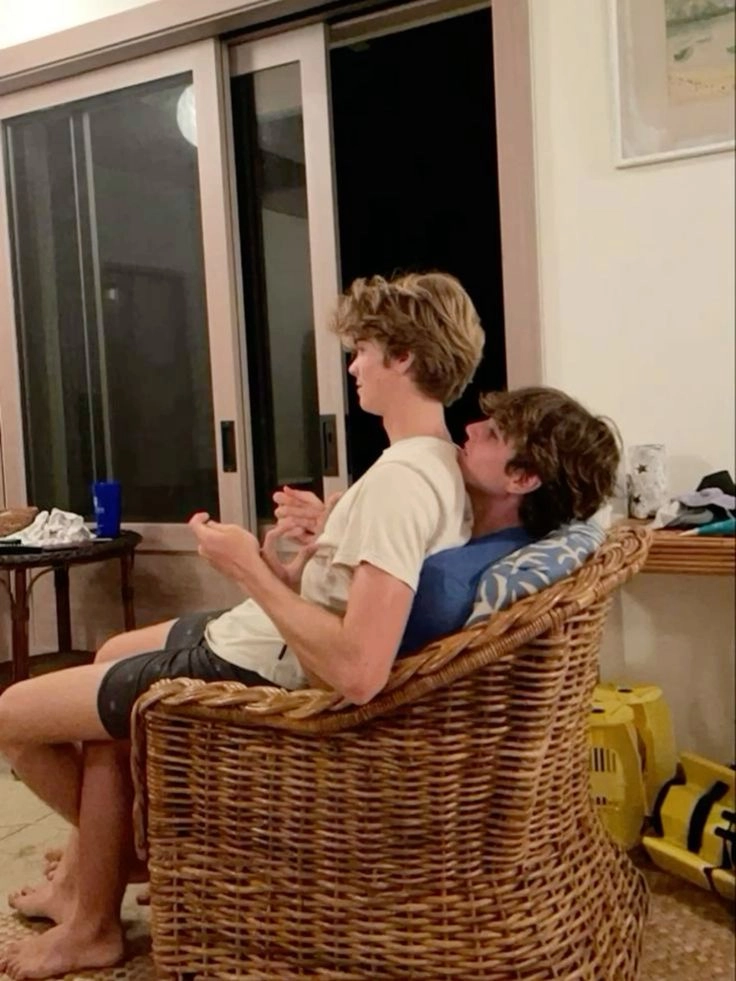 A couple of people sitting on top of a wicker chair.