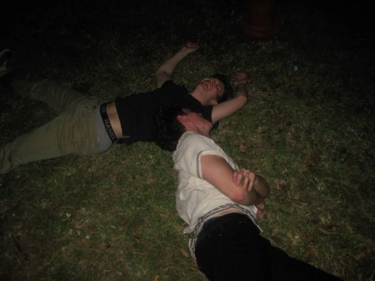 A group of people laying on top of a grass covered field.
