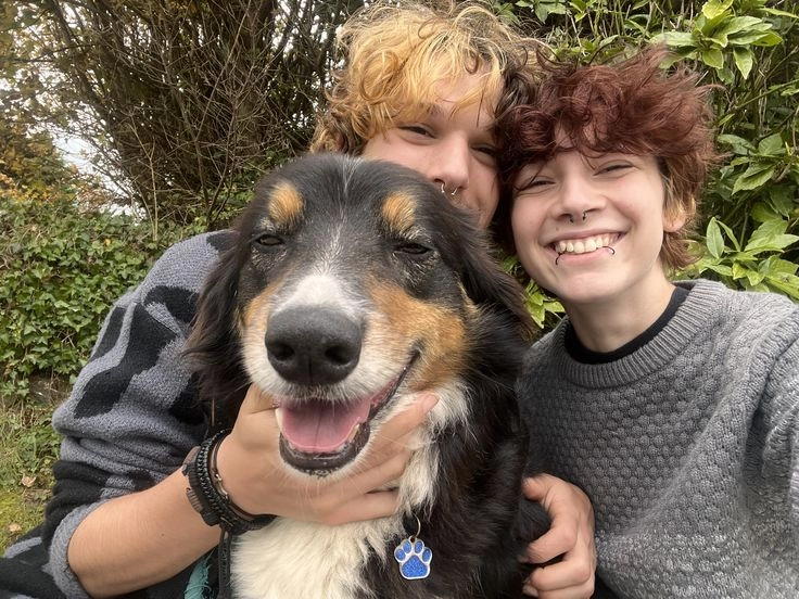 A group of young people posing for a picture with a dog.