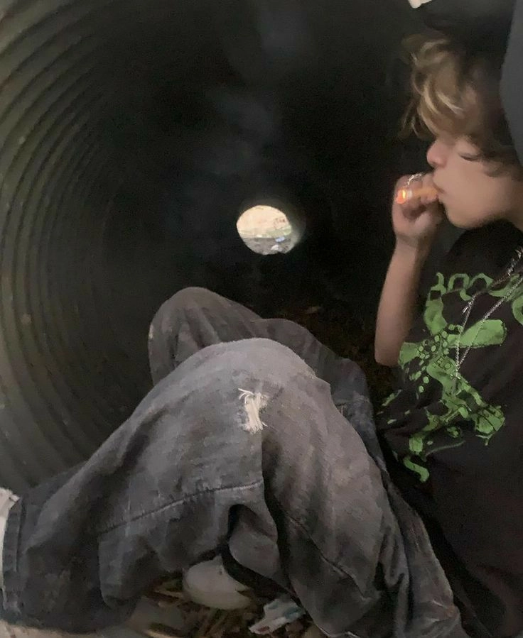 A young boy sitting on the ground next to a pile of clothes.