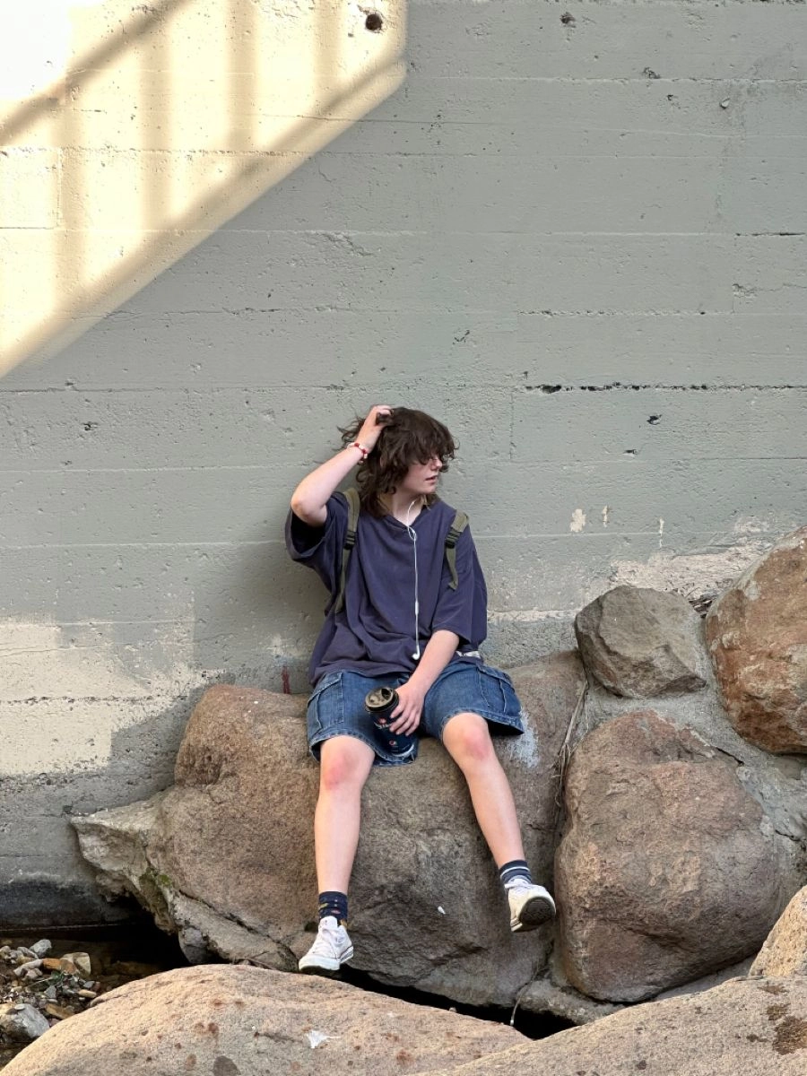 A man sitting on top of a large rock.
