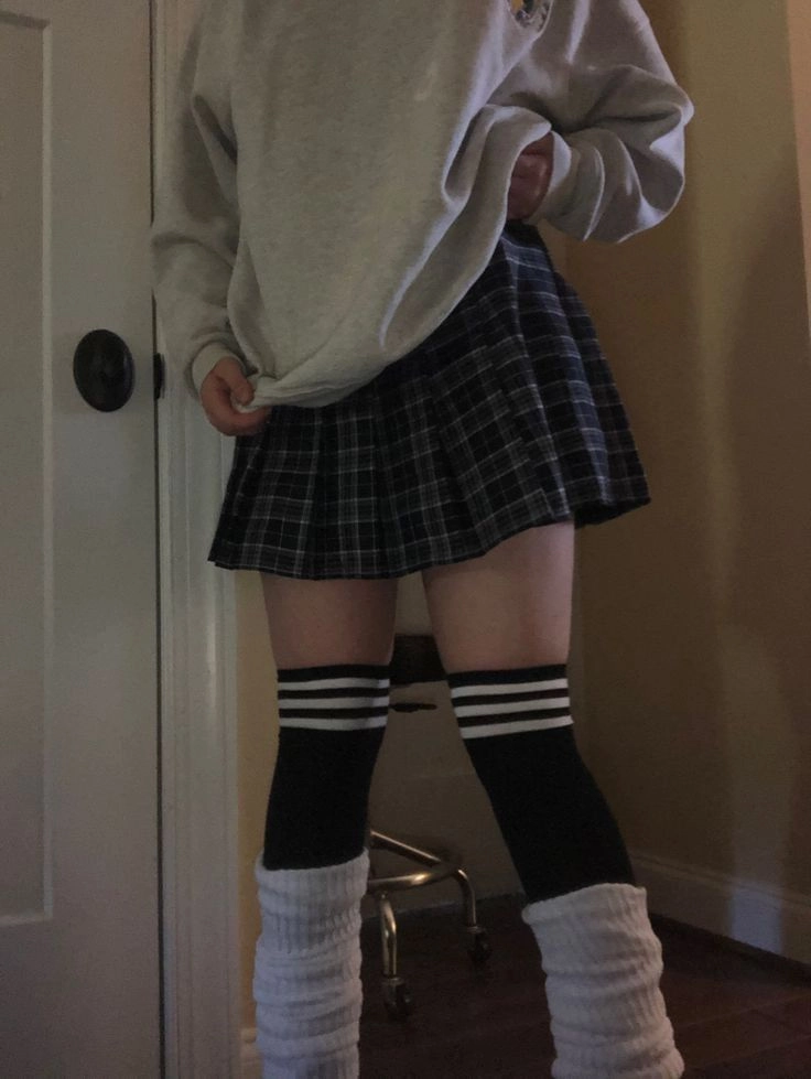 A woman in a plaid skirt and knee high socks.