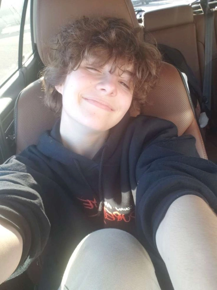 A young man sitting in the back seat of a car.