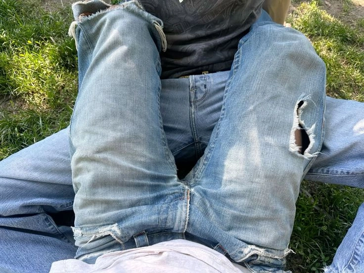 A pile of ripped jeans sitting on top of a grass covered field.