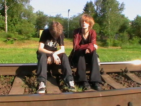 A group of young men sitting on top of a train track.