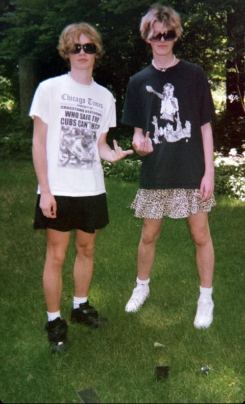 A couple of young men standing next to each other in the grass.