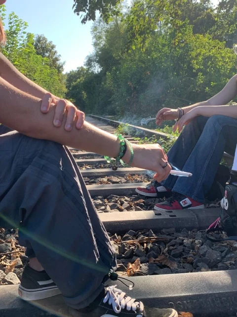 A group of people sitting on top of a train track.