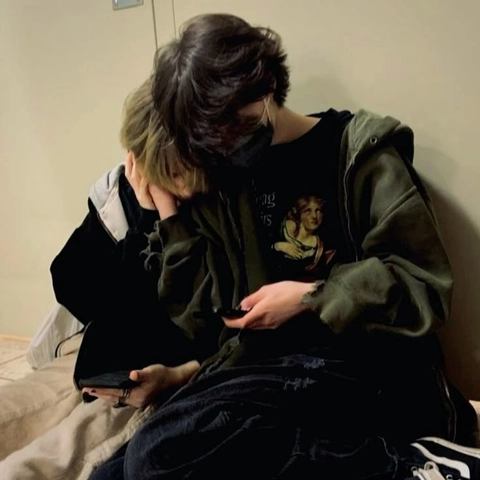 A couple of people sitting on top of a bed.