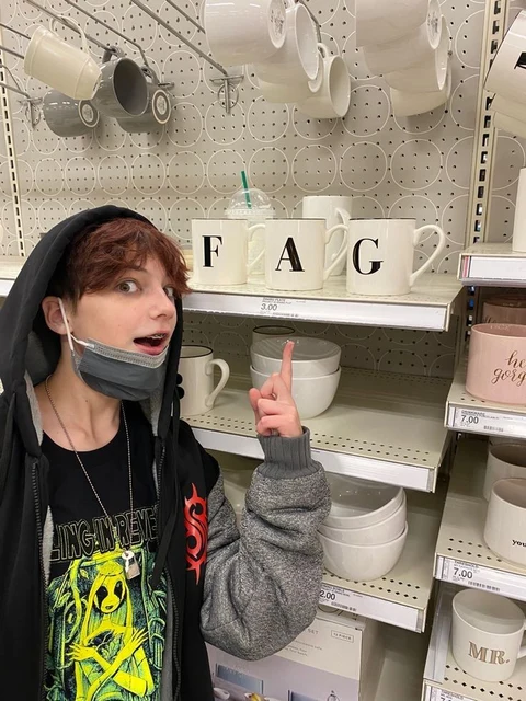 A woman wearing a face mask in front of a shelf of cups.