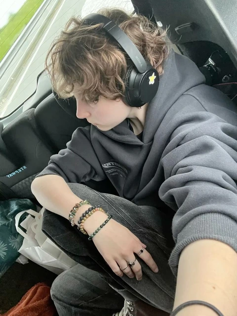 A young man wearing headphones sitting on a bus.