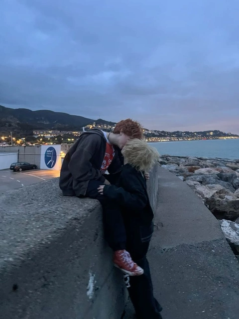 A man and a woman sitting on a stone wall.