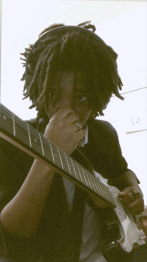 A man with dreadlocks playing a guitar.