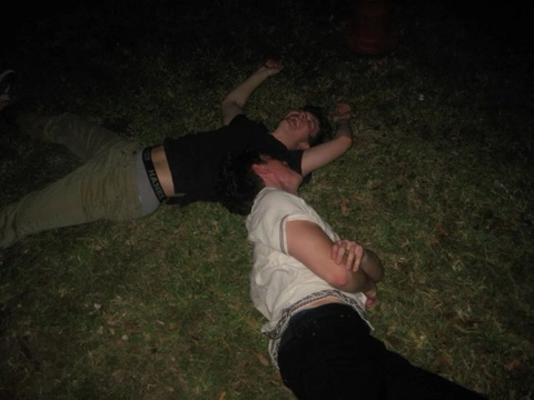 A couple of people laying on top of a lush green field.
