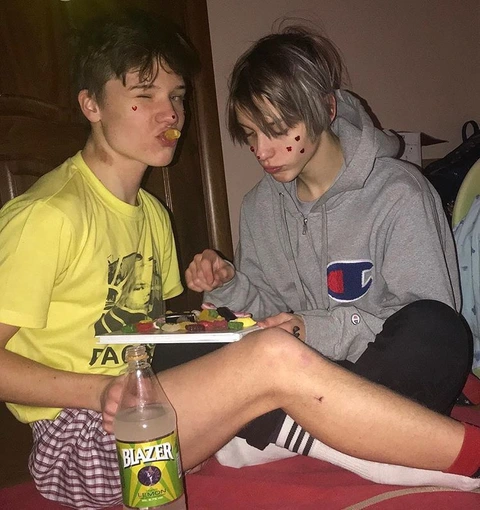 A couple of young men sitting next to each other eating food.