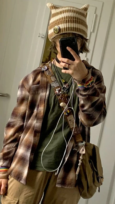 A man in a plaid jacket and hat taking a selfie.