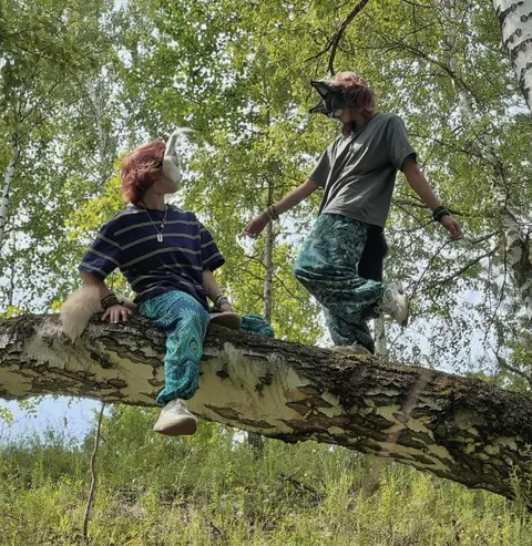 A couple of people sitting on top of a tree branch.