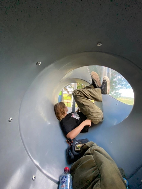 A couple of people laying on top of a metal slide.