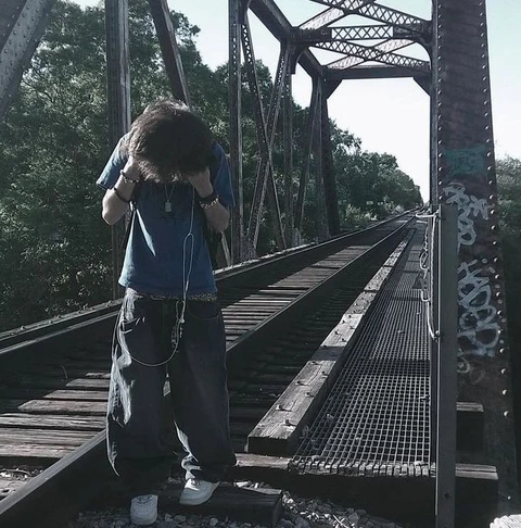 A man standing on a bridge with his head in his hands.