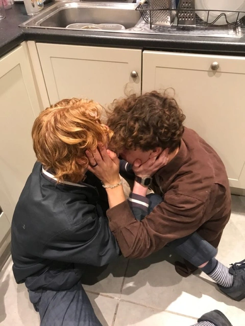 A couple of people that are sitting in a kitchen.