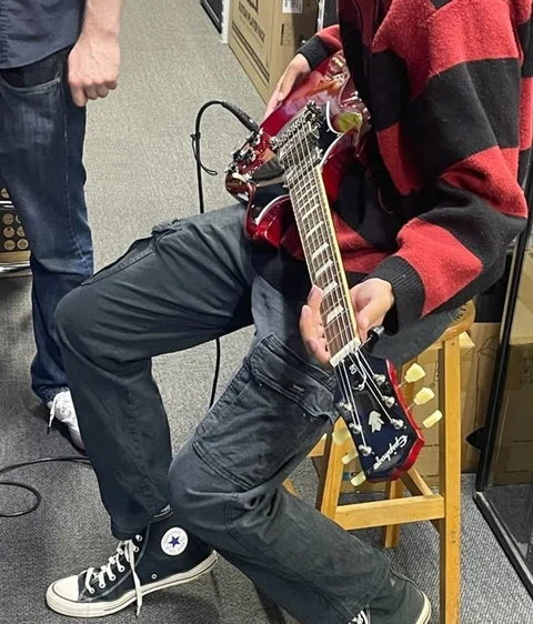 A man sitting on a stool playing a guitar.