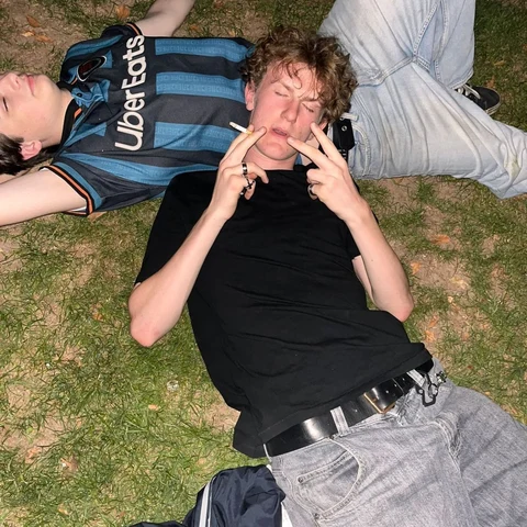 A group of young men laying on top of a grass covered field.