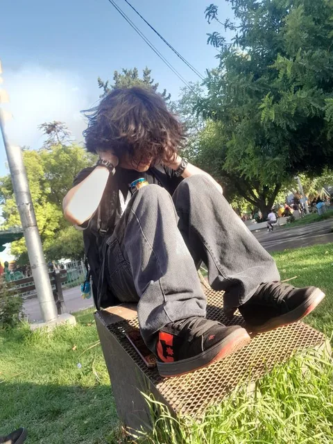 A man sitting on top of a metal chair in the grass.