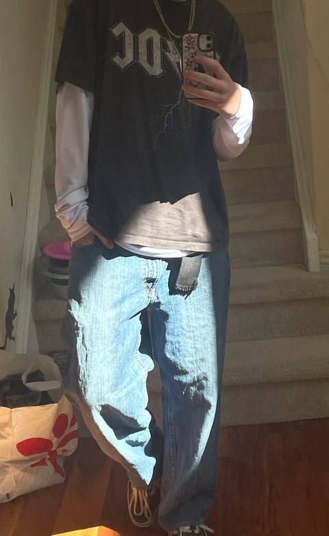 A man taking a picture of himself in ripped jeans.