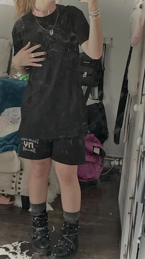 A woman in a black shirt and shorts standing in front of a mirror.