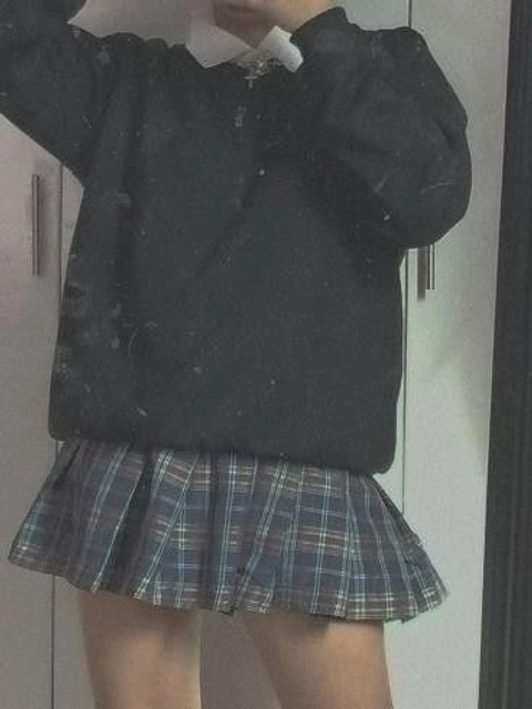 a woman in a black sweater and plaid skirt