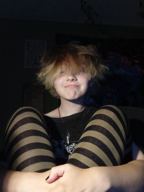 A young man with blonde hair sitting on a couch.