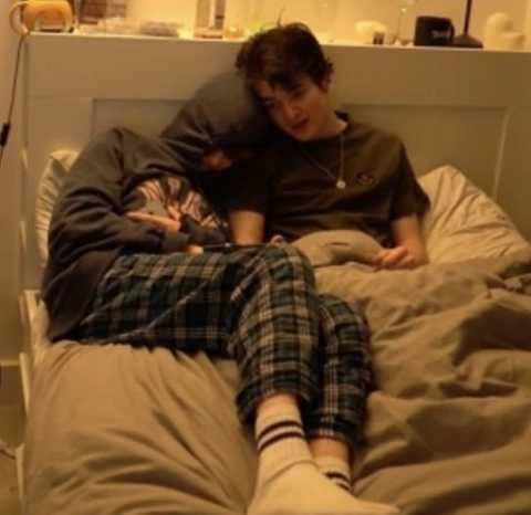 A couple of people sitting on top of a bed.