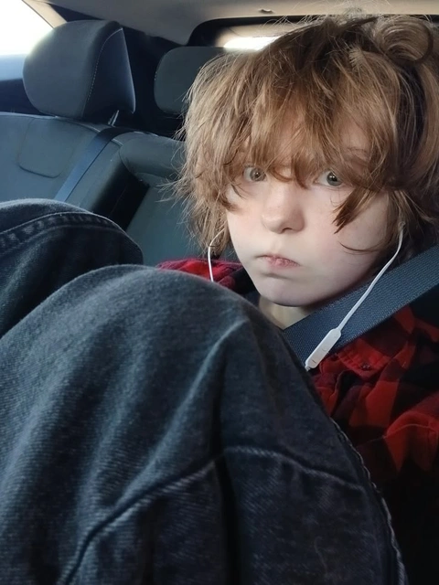 A little boy sitting in the back seat of a car.
