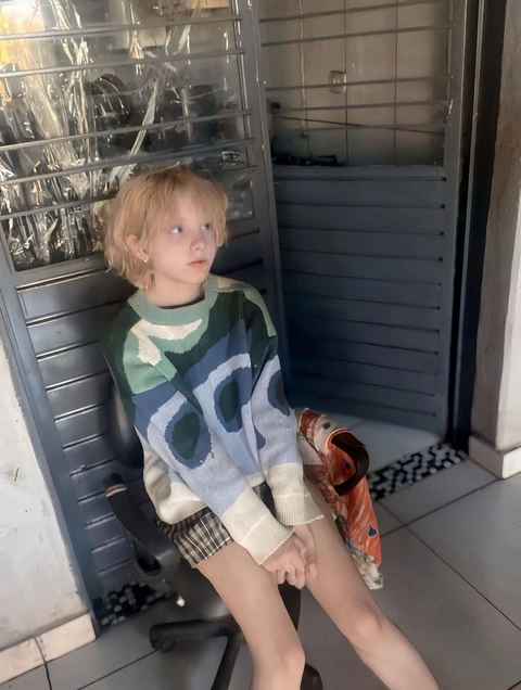 A little girl sitting on a chair in front of a mirror.