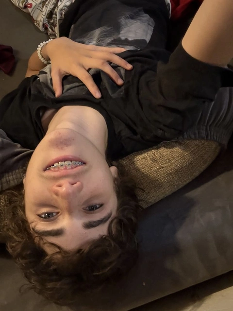 A woman laying on top of a couch with her hands on her head.