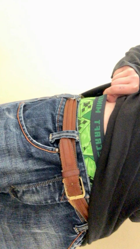 A pair of jeans with a green and black bag.