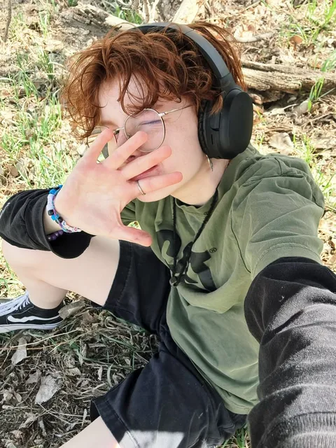 A woman with headphones covering her eyes with her hands.