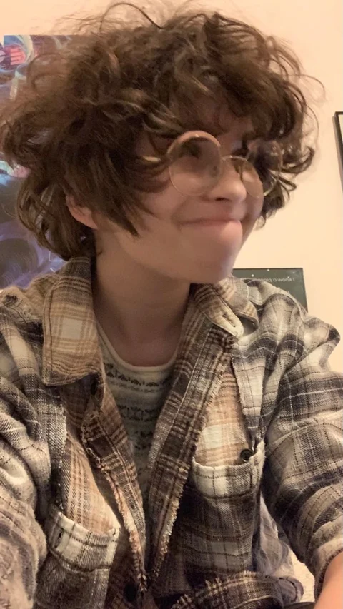 A woman with curly hair wearing a plaid shirt.
