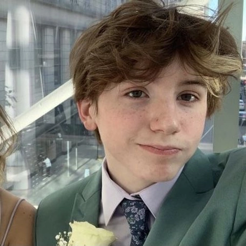 A young boy in a green suit and tie.