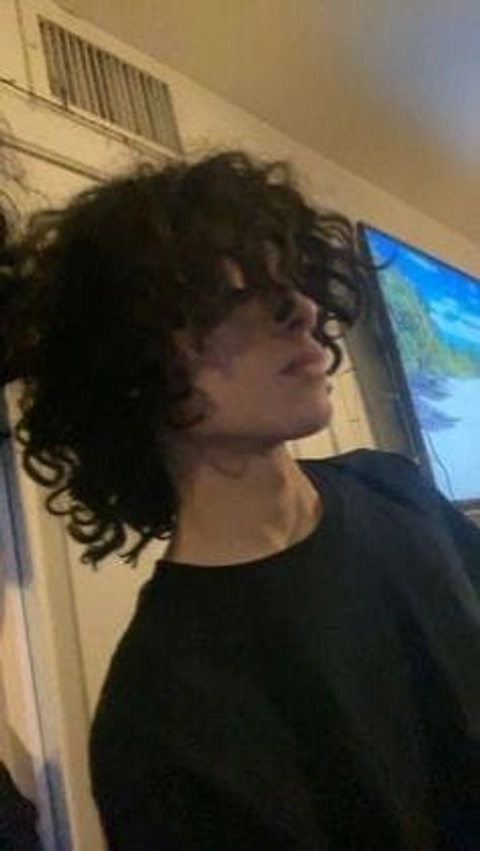 A woman with curly hair standing in front of a window.