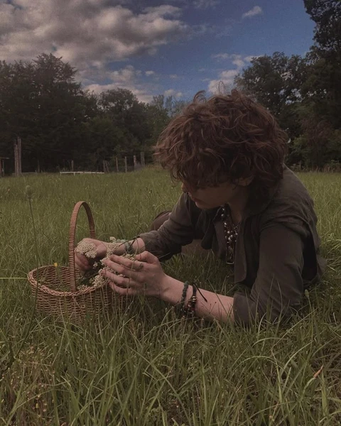 A woman kneeling in a field of tall grass holding a basket.