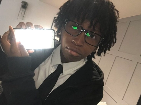 A young man with glasses taking a selfie with his cell phone.
