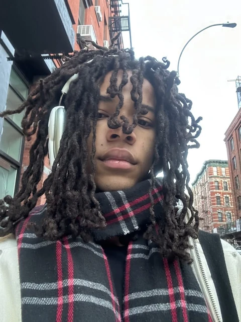 A woman with dreadlocks standing in front of a building.