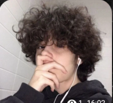 A young man with curly hair wearing headphones.