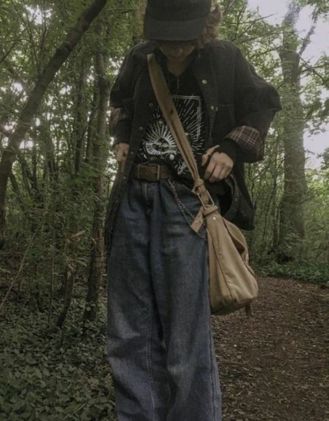 A woman walking through a forest carrying a bag.