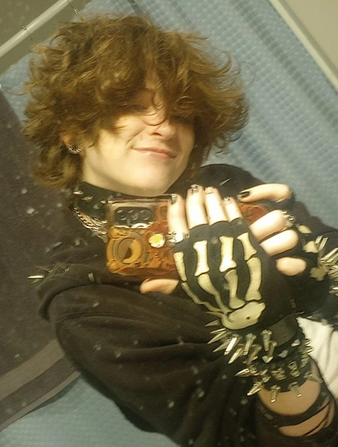 A man with curly hair holding a pair of gloves.