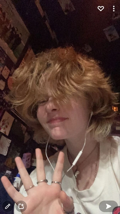 A woman with blonde hair and a white shirt is making a peace sign.