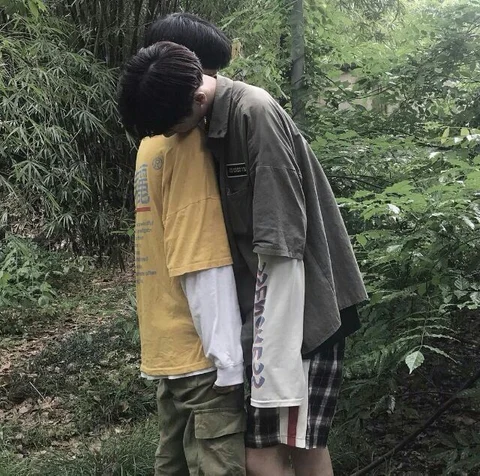 A couple of men standing next to each other in the woods.