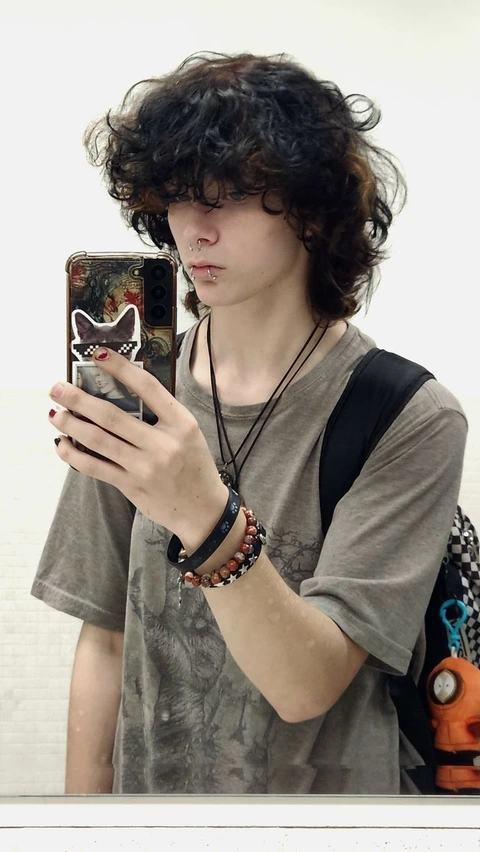 A man with curly hair holding a cell phone.